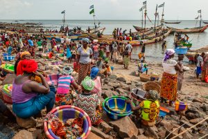 Busy traffic on beach in Tombo Harbour, Sierra Leone. Women are waiting for more fishing boats to arrive.