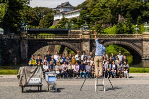 Group photographer demands attention in front of the Japanese Imperial Palace. Photoshooting in front of the Tenno Palace in Chiyoda (Tokyo), Japan