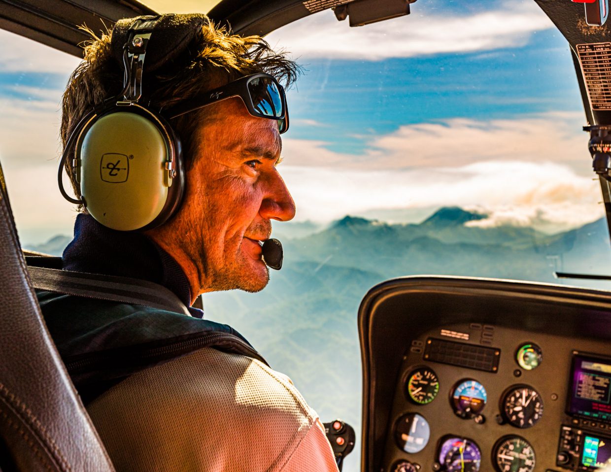 Helicopter pilot in his cockpit in front of the volcanoes of Bougainville, Papua New Guinea