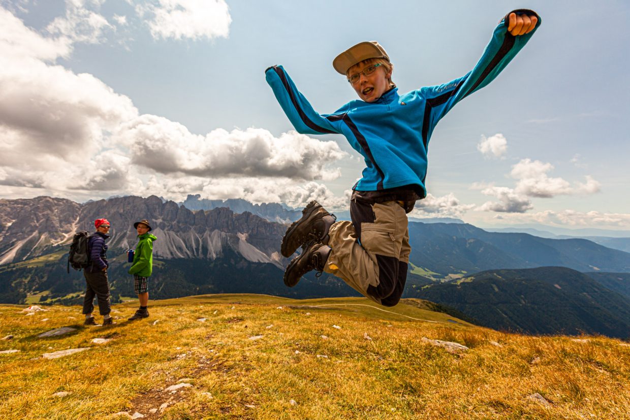 Young Hiker jumping in the Air in the mountains of Alto Adige, Italy