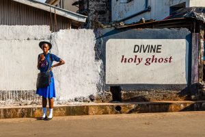"Divine holy ghost" - Student standing in front of religious inscription in Sierra Leone