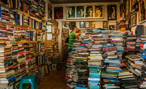 Book shop in San Jose, Costa Rica with piles of books stuffed on shelves and on the ground. In the backround you see  portraits of the Beatles.