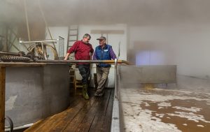 Shortly before the brewery fills with thick fog, Zoigl master brewer Sepp Neuber stands on the ship with a house brewer. Traditional Zoigl Brewery in Falkenberg, Germany